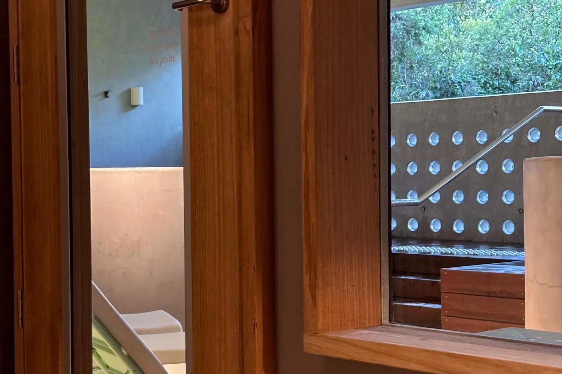 Janela de madeira da Comma, com vista para a área de banhos e para a vegetação